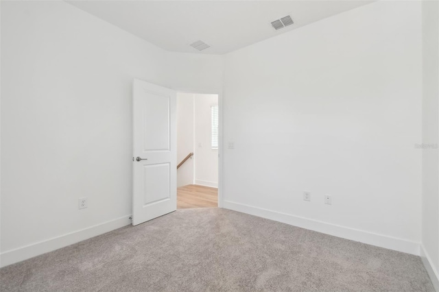 empty room with baseboards, visible vents, and light colored carpet