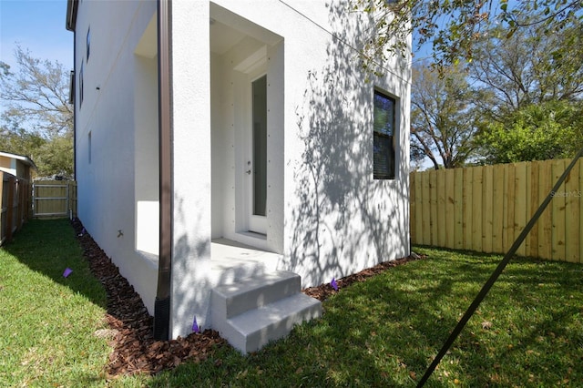 view of side of property with a yard, fence, and stucco siding