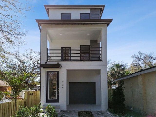 view of front facade featuring a balcony, fence, and stucco siding