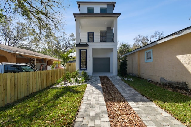 view of front of house with fence, a balcony, and stucco siding