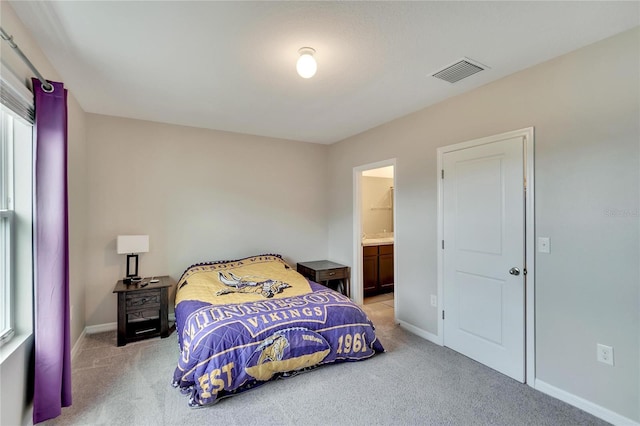 bedroom featuring connected bathroom and light colored carpet