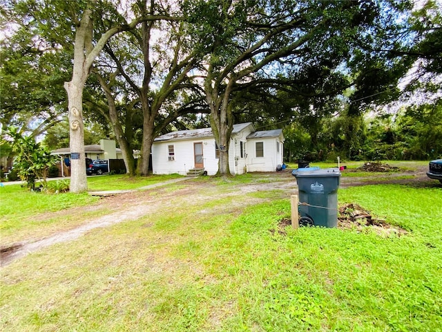 view of front of property featuring a front lawn and dirt driveway