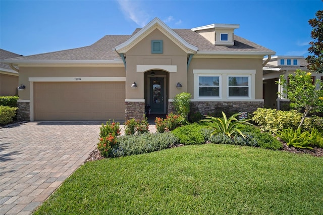 view of front of property with stone siding, decorative driveway, and stucco siding