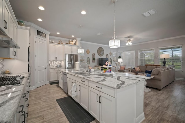 kitchen with white cabinets, stainless steel appliances, a kitchen island with sink, and sink