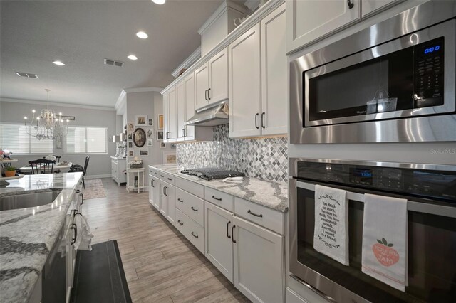 kitchen featuring an inviting chandelier, light hardwood / wood-style flooring, appliances with stainless steel finishes, white cabinets, and ornamental molding