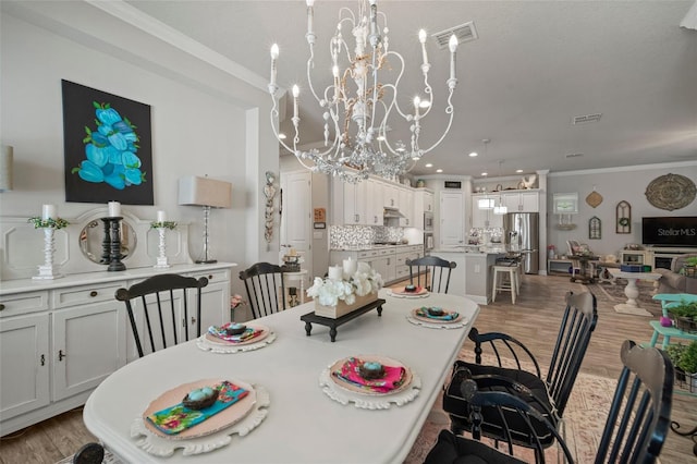 dining area featuring hardwood / wood-style floors, ornamental molding, and a chandelier