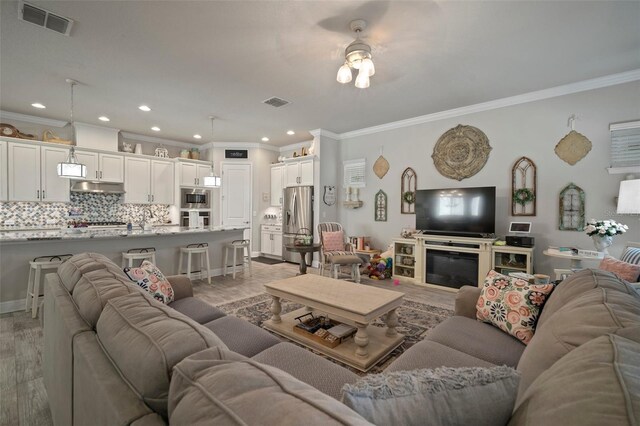 living room featuring crown molding, ceiling fan, and light wood-type flooring