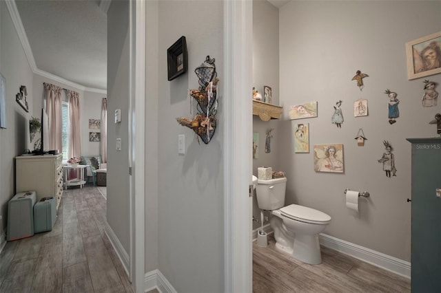 bathroom featuring toilet, ornamental molding, and hardwood / wood-style flooring