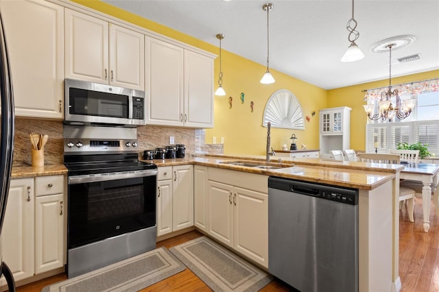 kitchen with backsplash, stainless steel appliances, kitchen peninsula, and light hardwood / wood-style flooring