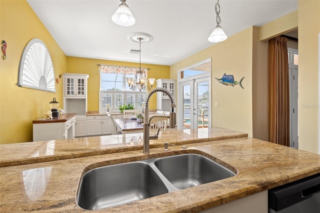 kitchen with sink, an inviting chandelier, dishwasher, white cabinetry, and hanging light fixtures