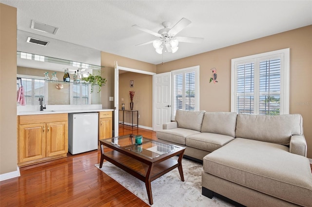 living room with hardwood / wood-style floors, sink, and ceiling fan