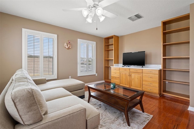 living room with ceiling fan, hardwood / wood-style flooring, and a textured ceiling