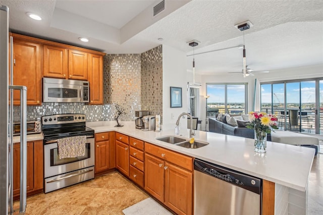 kitchen with pendant lighting, sink, a textured ceiling, appliances with stainless steel finishes, and kitchen peninsula