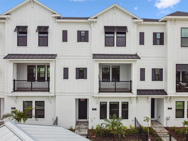 townhome / multi-family property with a standing seam roof, a balcony, and board and batten siding