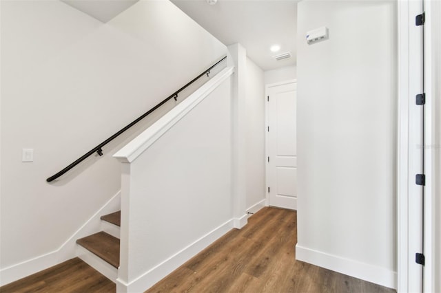 stairway with visible vents, baseboards, and wood finished floors