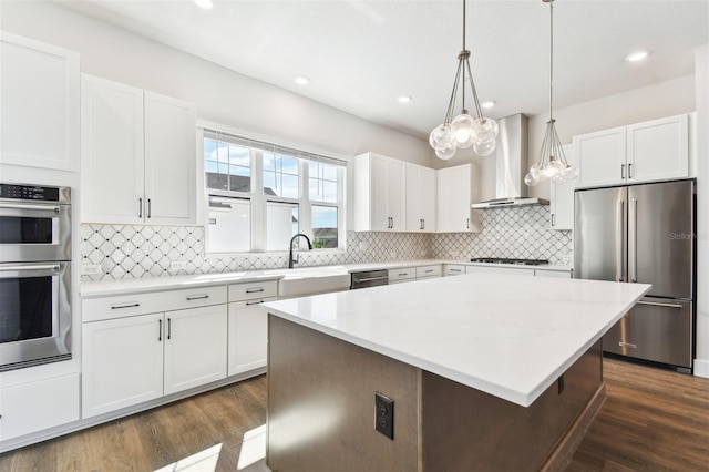 kitchen featuring dark wood-style floors, decorative backsplash, appliances with stainless steel finishes, and wall chimney exhaust hood