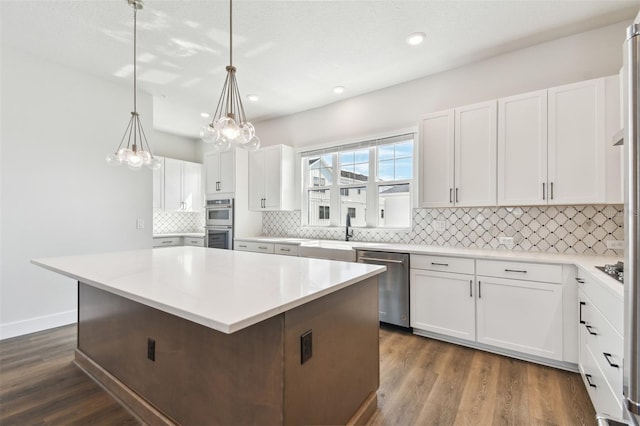 kitchen featuring stainless steel appliances, dark wood-type flooring, a kitchen island, and white cabinetry