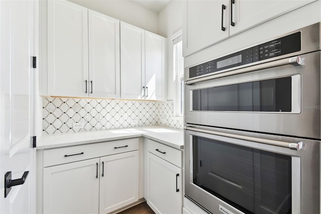 kitchen featuring backsplash, double oven, and white cabinetry