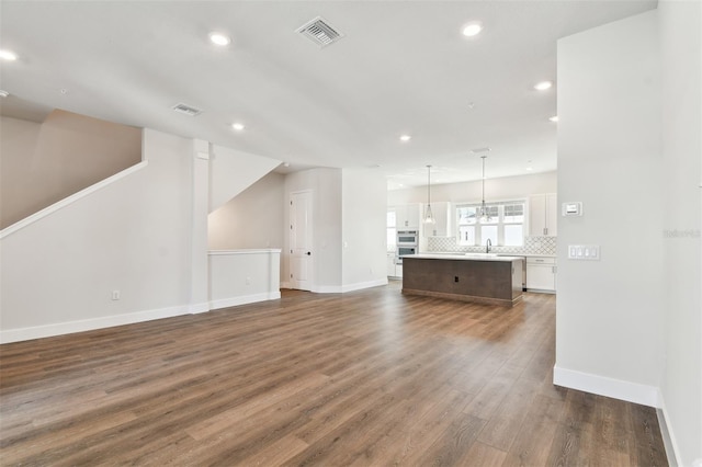 unfurnished living room featuring recessed lighting, visible vents, baseboards, and dark wood-style flooring