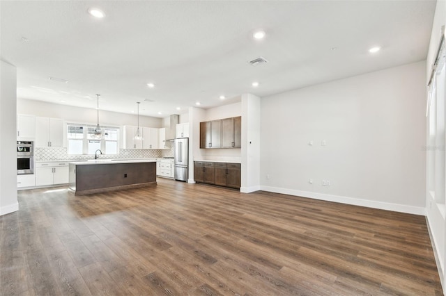 unfurnished living room with visible vents, a sink, dark wood-style floors, recessed lighting, and baseboards