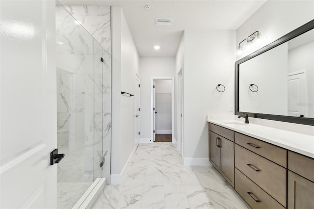 full bath with vanity, baseboards, a marble finish shower, a walk in closet, and marble finish floor