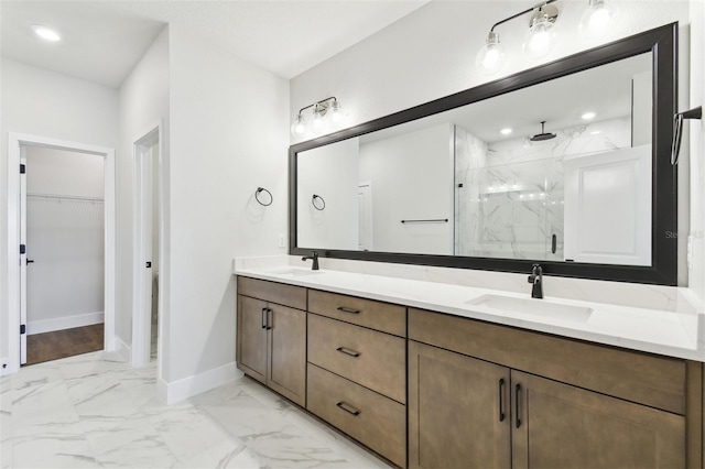 bathroom with a walk in closet, marble finish floor, a sink, a marble finish shower, and baseboards