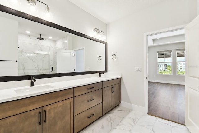 bathroom featuring a marble finish shower, marble finish floor, baseboards, and a sink