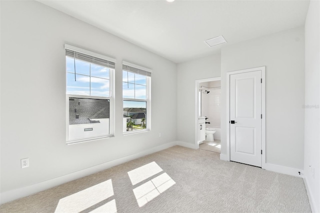 unfurnished bedroom with ensuite bath, light colored carpet, and baseboards