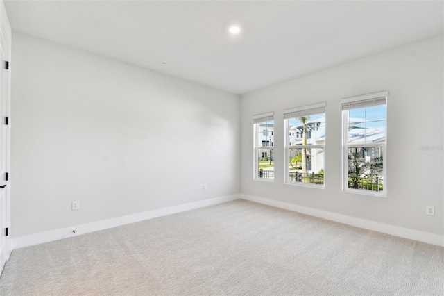 empty room featuring light colored carpet and baseboards