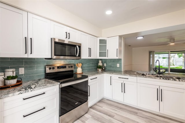 kitchen featuring tasteful backsplash, stainless steel appliances, light stone countertops, ceiling fan, and white cabinets