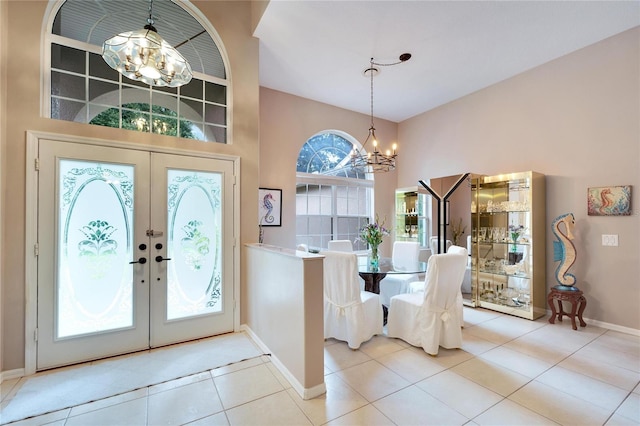 tiled entrance foyer with french doors, a chandelier, and a high ceiling