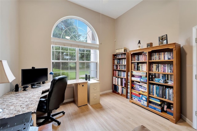 office featuring high vaulted ceiling and light hardwood / wood-style flooring