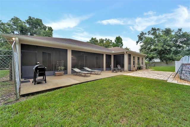 rear view of property with a sunroom, a patio area, and a lawn