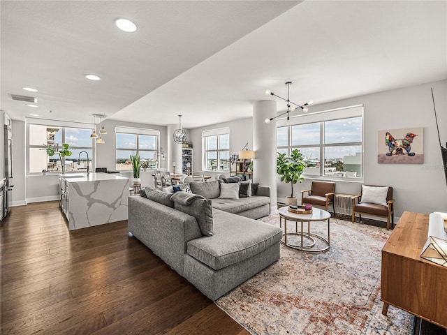 living room with dark hardwood / wood-style flooring, plenty of natural light, and an inviting chandelier