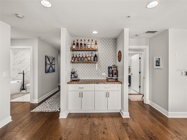 bar featuring white cabinets, backsplash, and dark hardwood / wood-style floors