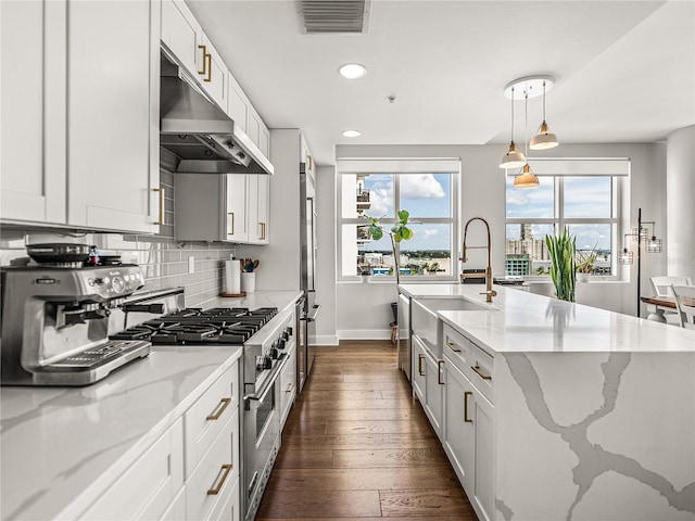 kitchen with double oven range, light stone counters, decorative light fixtures, and dark hardwood / wood-style flooring