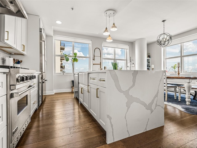 kitchen featuring designer stove, custom range hood, dark hardwood / wood-style flooring, and decorative light fixtures