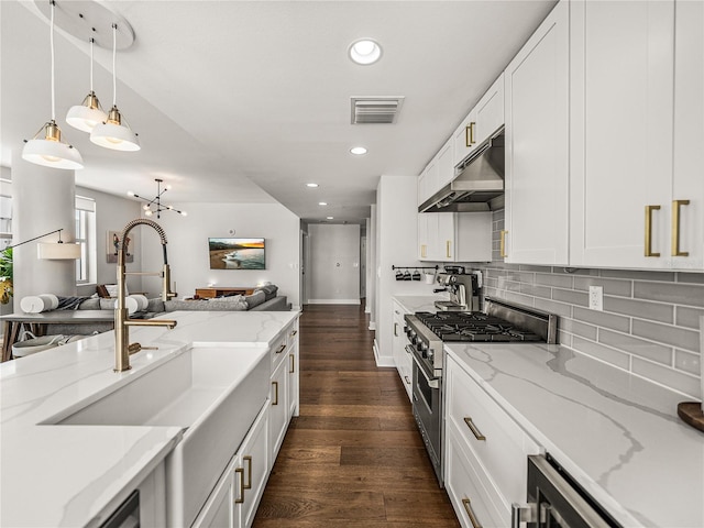 kitchen with white cabinetry, light stone counters, pendant lighting, dark wood-type flooring, and stainless steel stove