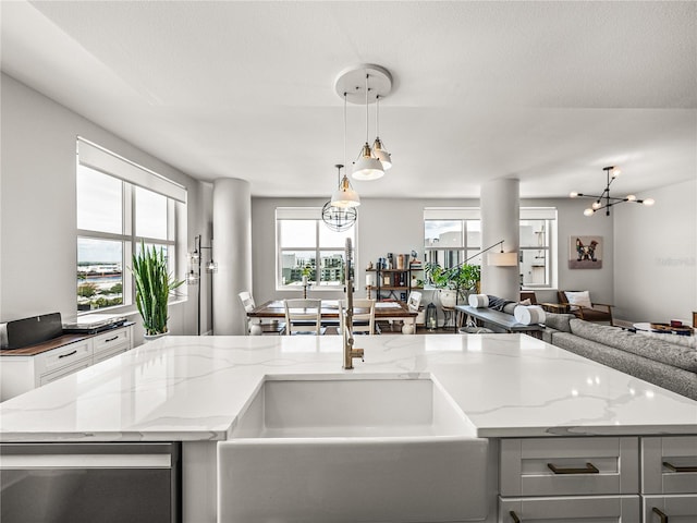 kitchen with decorative light fixtures, a chandelier, white cabinetry, sink, and light stone counters