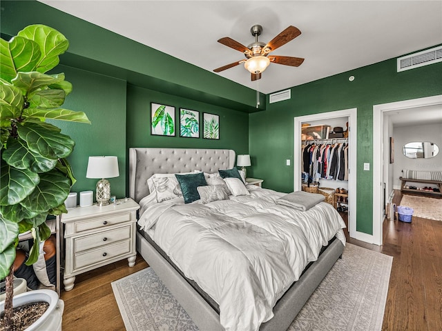 bedroom with dark hardwood / wood-style flooring, a closet, a walk in closet, and ceiling fan