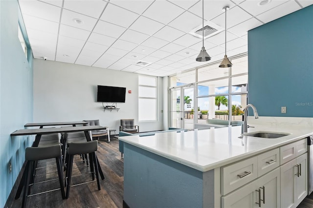 kitchen with sink, a drop ceiling, floor to ceiling windows, dark hardwood / wood-style floors, and hanging light fixtures