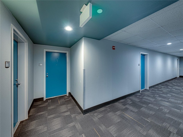 foyer with dark colored carpet and a paneled ceiling