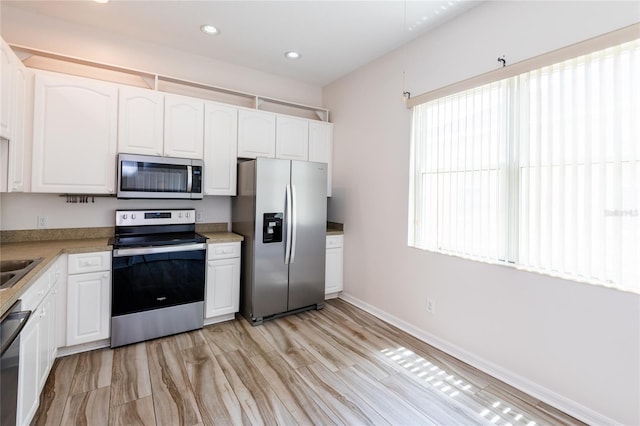 kitchen featuring appliances with stainless steel finishes, a wealth of natural light, and white cabinetry