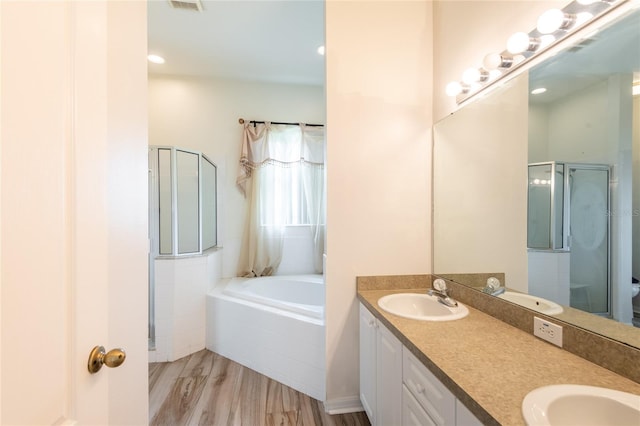 bathroom with dual bowl vanity, hardwood / wood-style flooring, and independent shower and bath