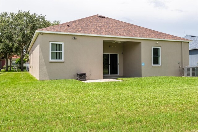 rear view of house with cooling unit and a yard