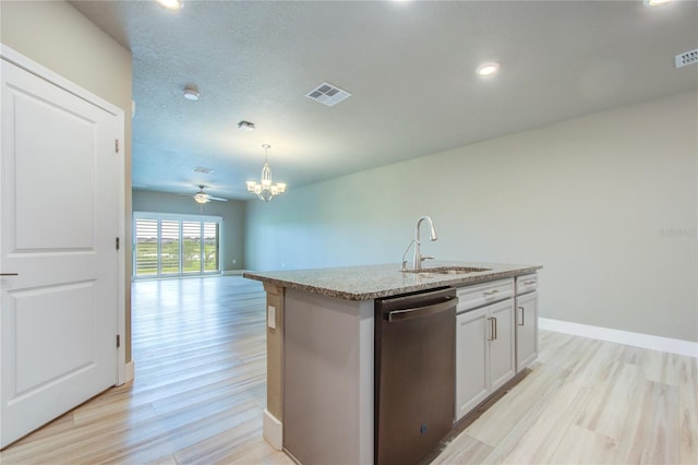 kitchen featuring light hardwood / wood-style flooring, hanging light fixtures, ceiling fan with notable chandelier, an island with sink, and dishwasher