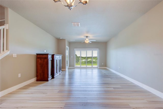 unfurnished living room with light hardwood / wood-style floors, ceiling fan with notable chandelier, and a textured ceiling