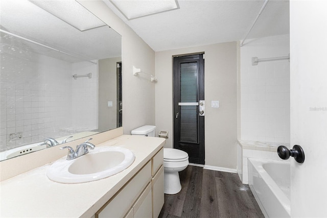 full bathroom with hardwood / wood-style floors, vanity, tiled shower / bath, and toilet