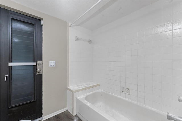 bathroom featuring wood-type flooring, a textured ceiling, and tiled shower / bath