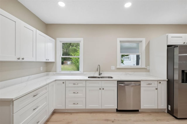 kitchen featuring light stone countertops, stainless steel appliances, white cabinetry, and sink